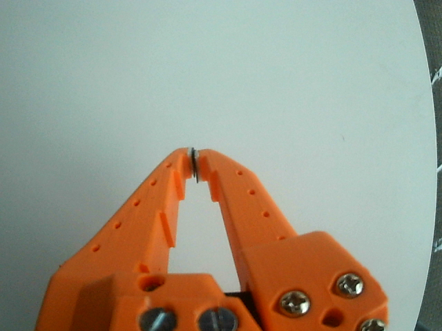 Close-up from a gripper camera: orange gripper, white table, no cubes in view.
